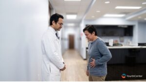 A compassionate gastroenterologist pearland texas evaluating a patient experiencing acute lower left abdominal pain down a clinic hallway corridor for an expert gi doctor pearland checkup.