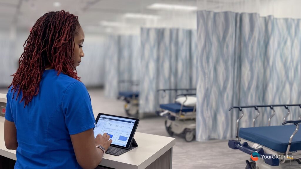 A clinical nurse using a digital tablet at the desk to organize liver function blood tests and diagnostic screening intervals near an endoscopy manvel tx clinic for a trusted gi specialist pearland.
