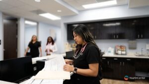 A supportive clinical nurse managing patient check-in charts at a reception desk for an experienced hemorrhoids specialist south houston providing advanced hemorrhoid treatment houston tx.